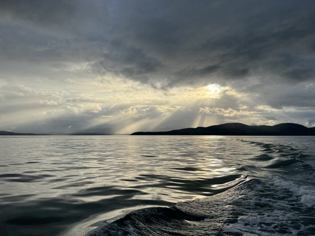 Southeast Alaska water at sunset near Juneau with sun rays breaking through storm clouds over the Inside Passage